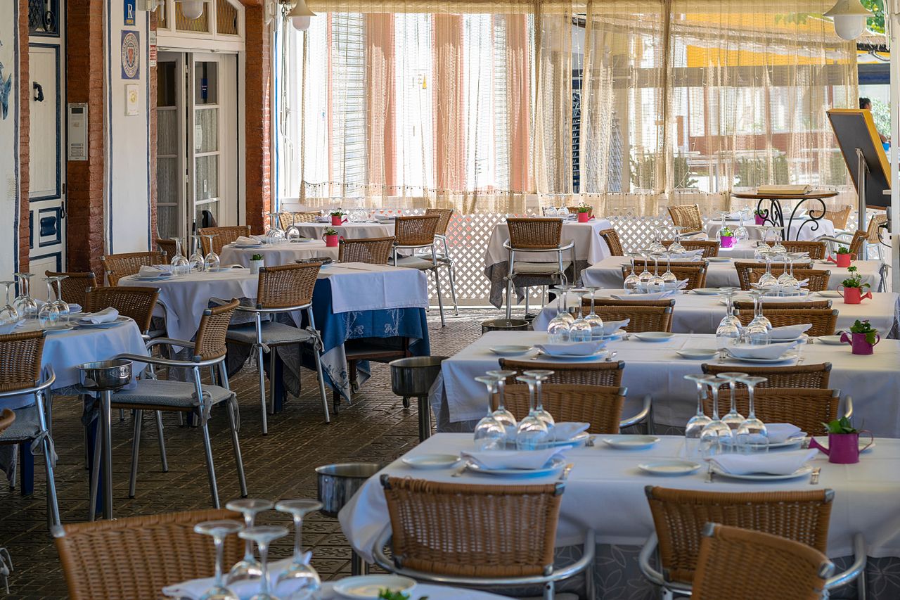 İspanya'nın Sitges kentinde doğal ışık alan, düzenli masalarıyla açık hava yemek alanı