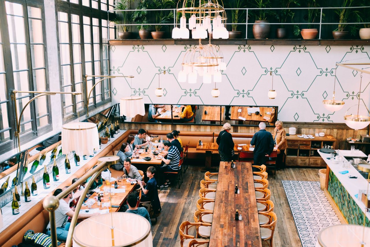 Ahşap masaları ve yemek yiyen konuklarıyla geniş, şık restoran