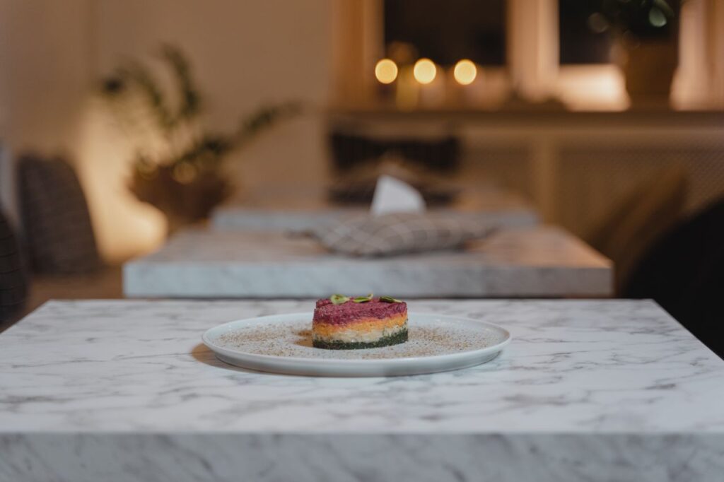 A beautifully presented gourmet dish on a marble table in a cozy restaurant setting with warm lighting.