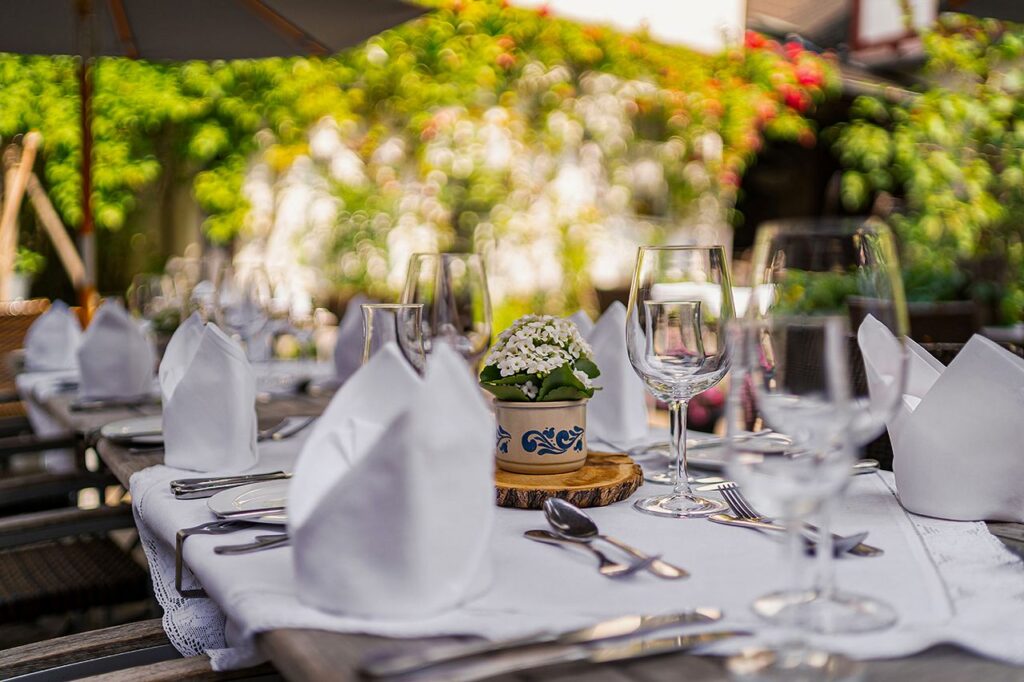 Elegant outdoor dining setup with white napkins and floral centerpiece, perfect for celebrations.